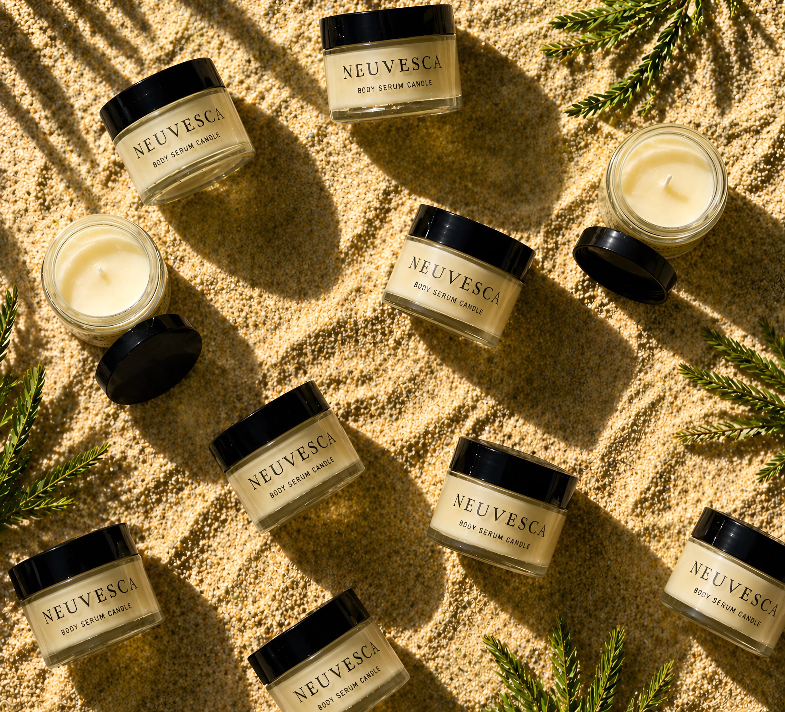 Three Neuvesca body serum candles burning beside dried botanicals.